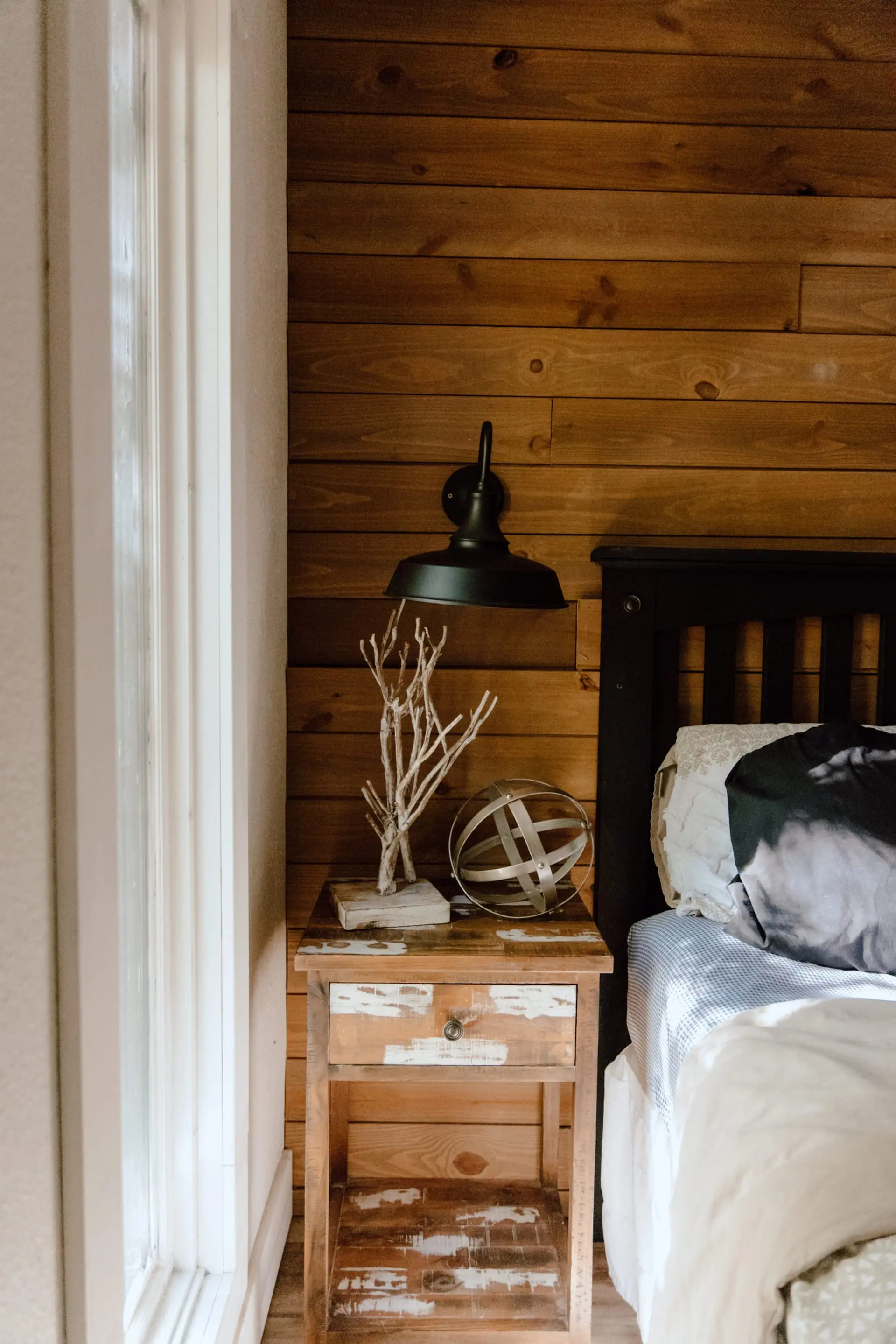 Bedroom 1 detail — a bedside table with a black lamp and a driftwood sculpture
