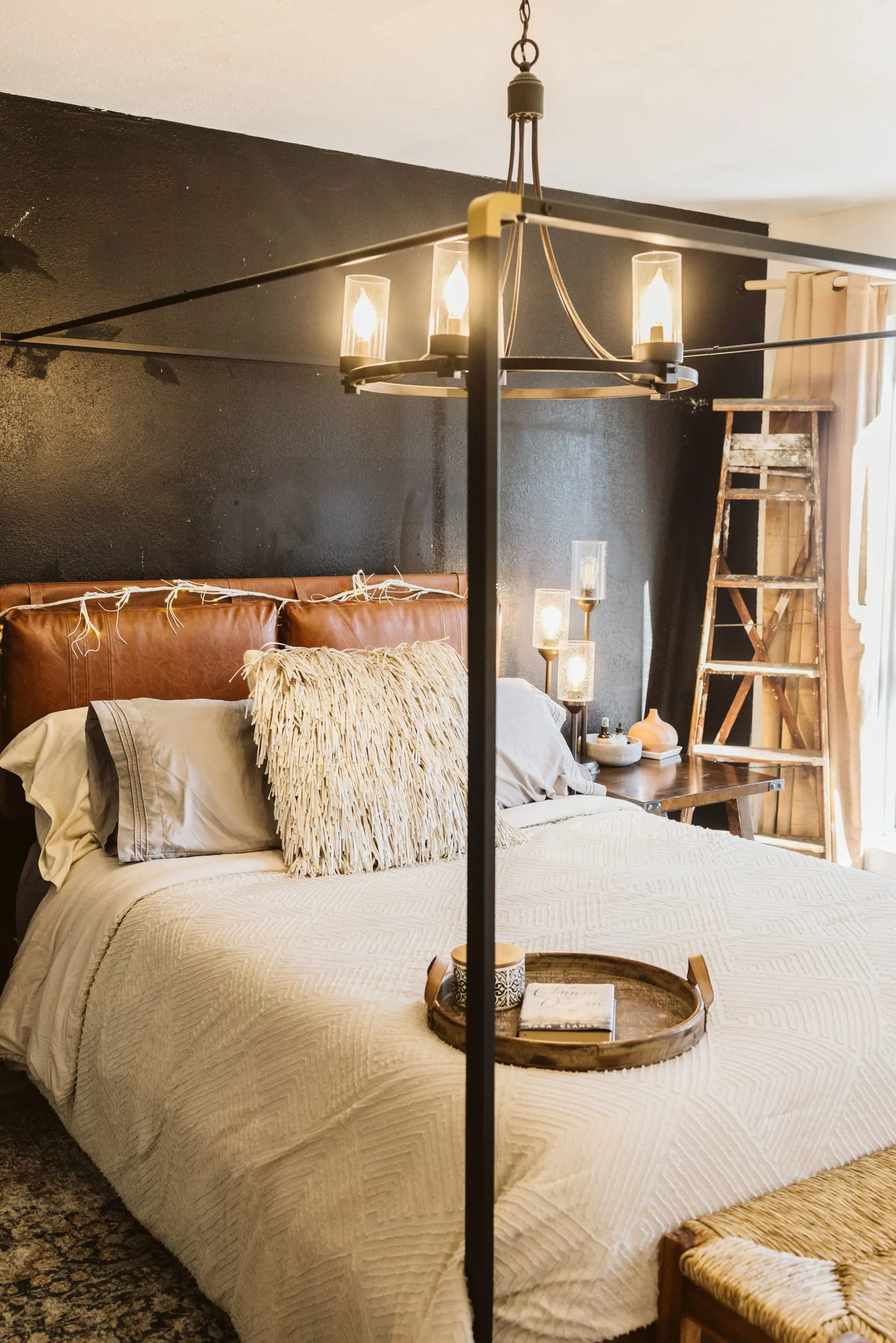 Bedroom 2 — a queen bed with a leather headboard, sheepskin pillows and a lantern against dark walls