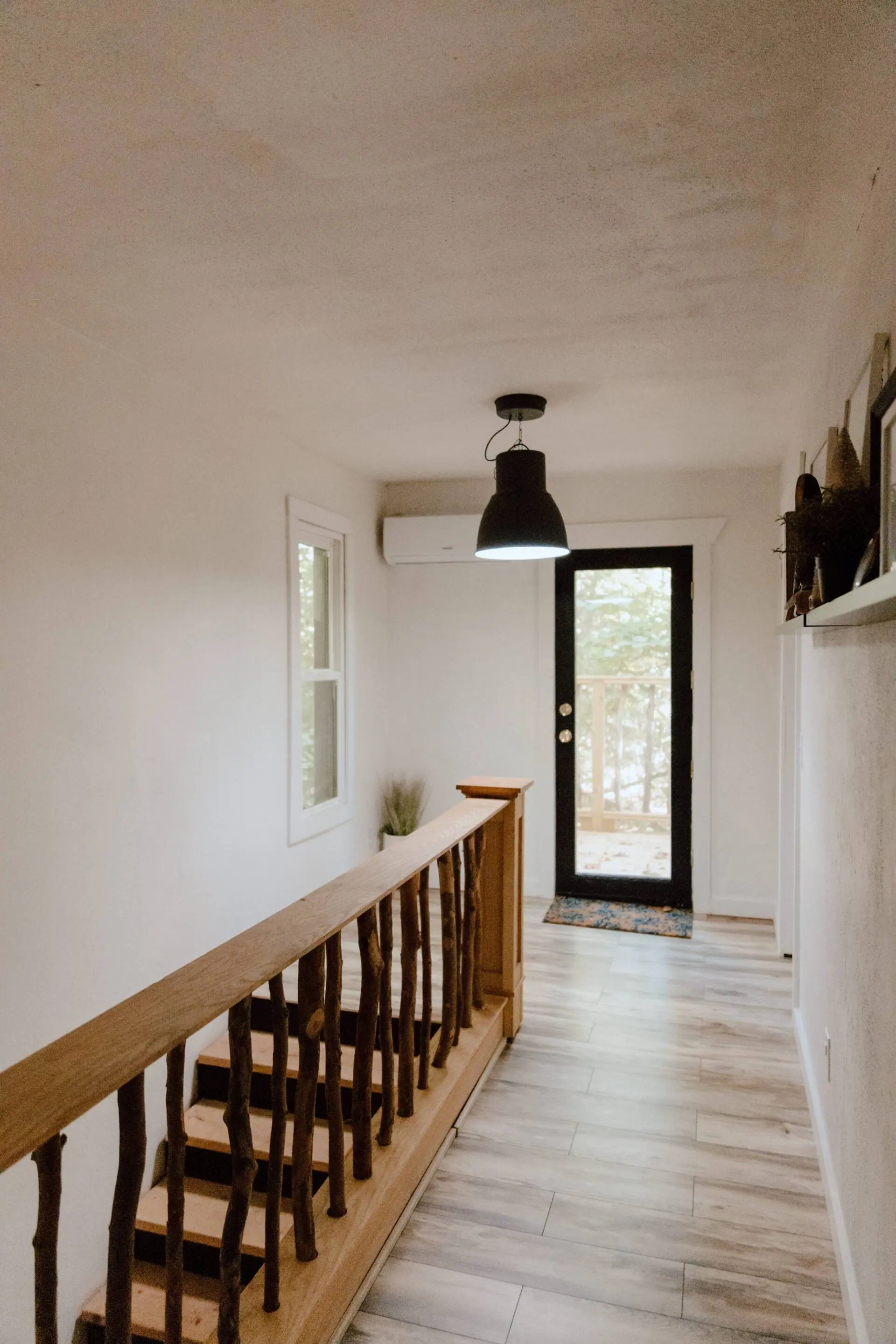 The upstairs landing with a branch-built railing and a door out to the tree-line porch