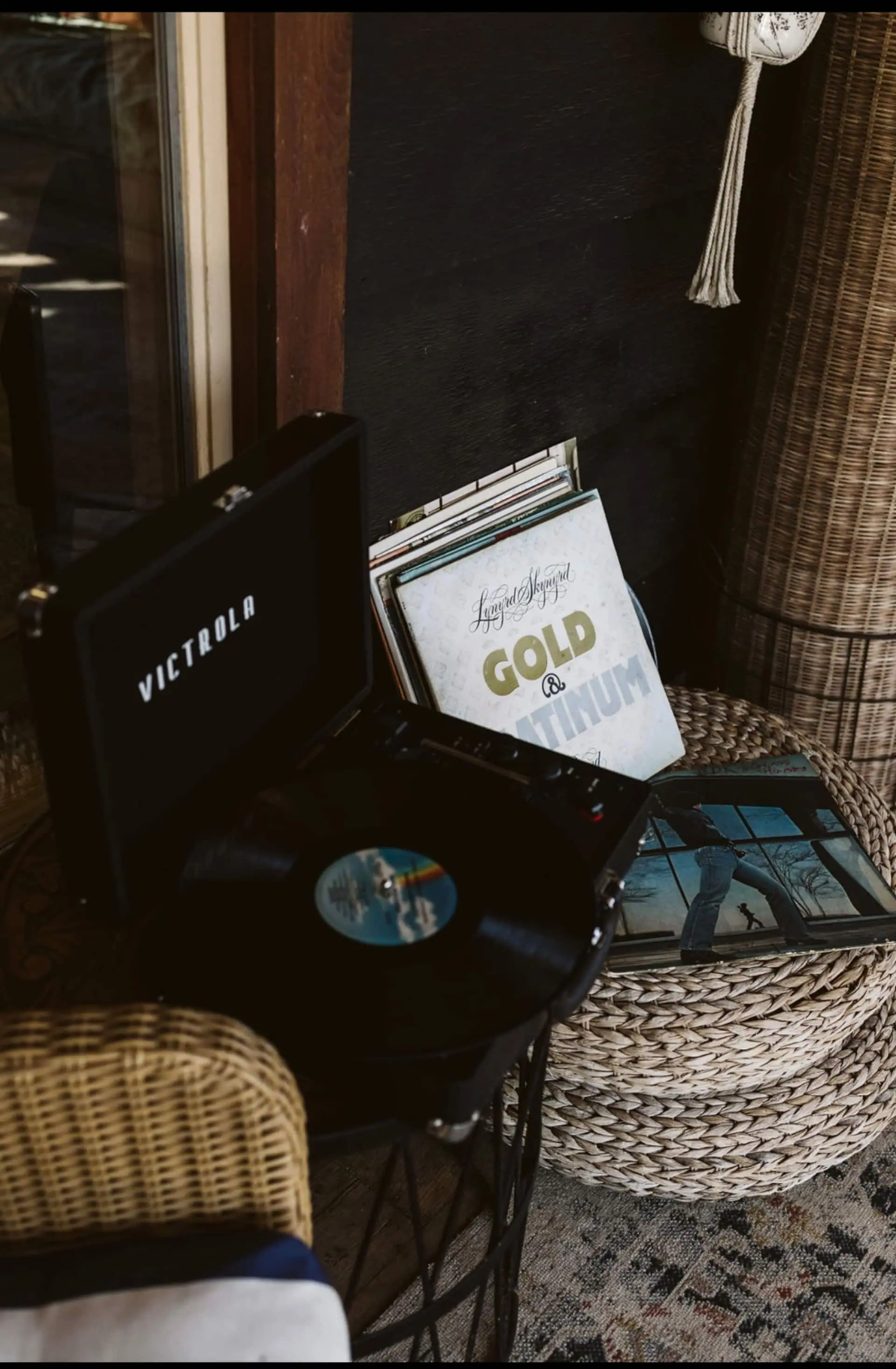 A Victrola record player and a stack of vinyl records on the cabin porch