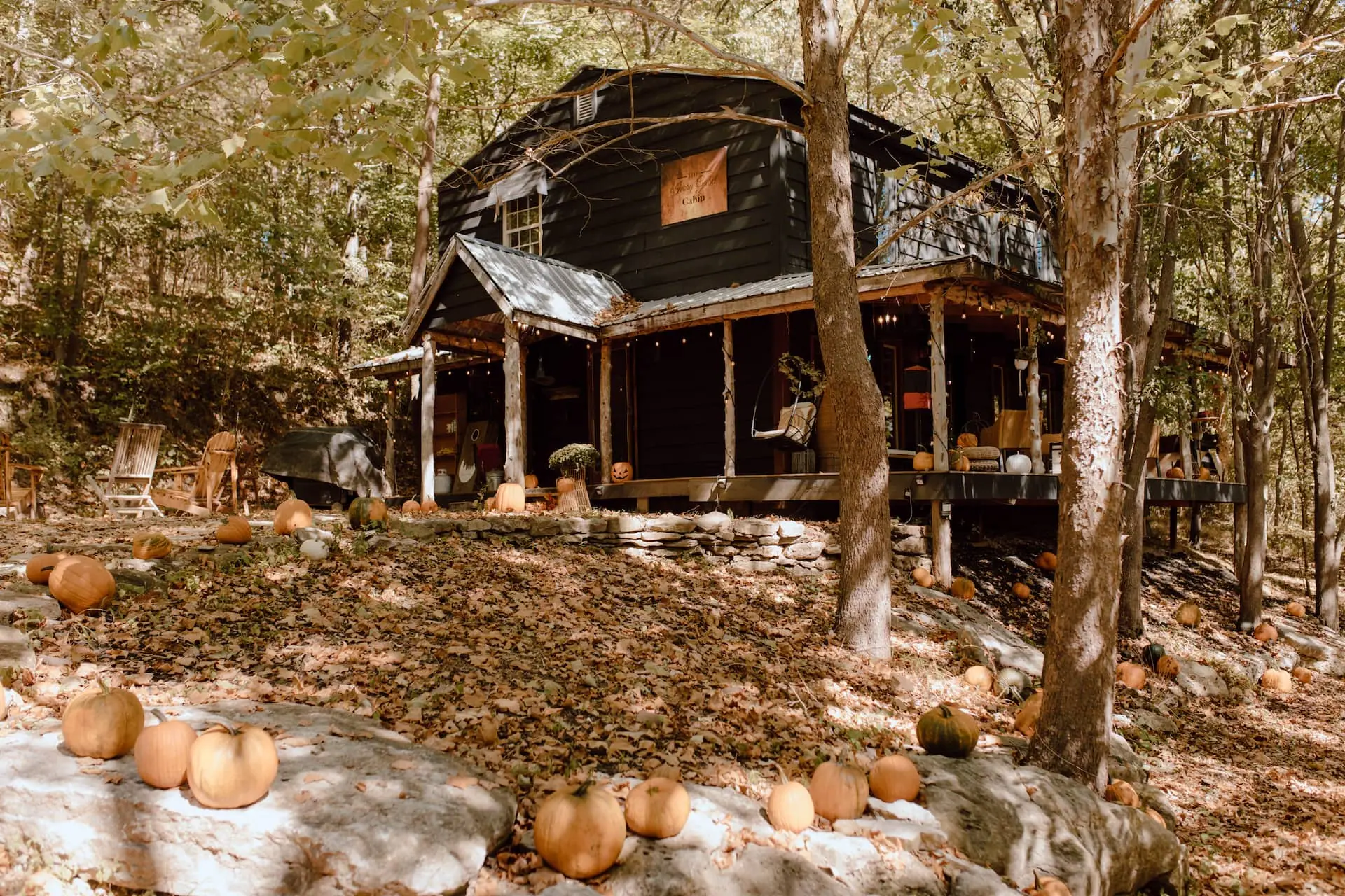 The cabin tucked into the woodland, its porch wrapping around the hillside
