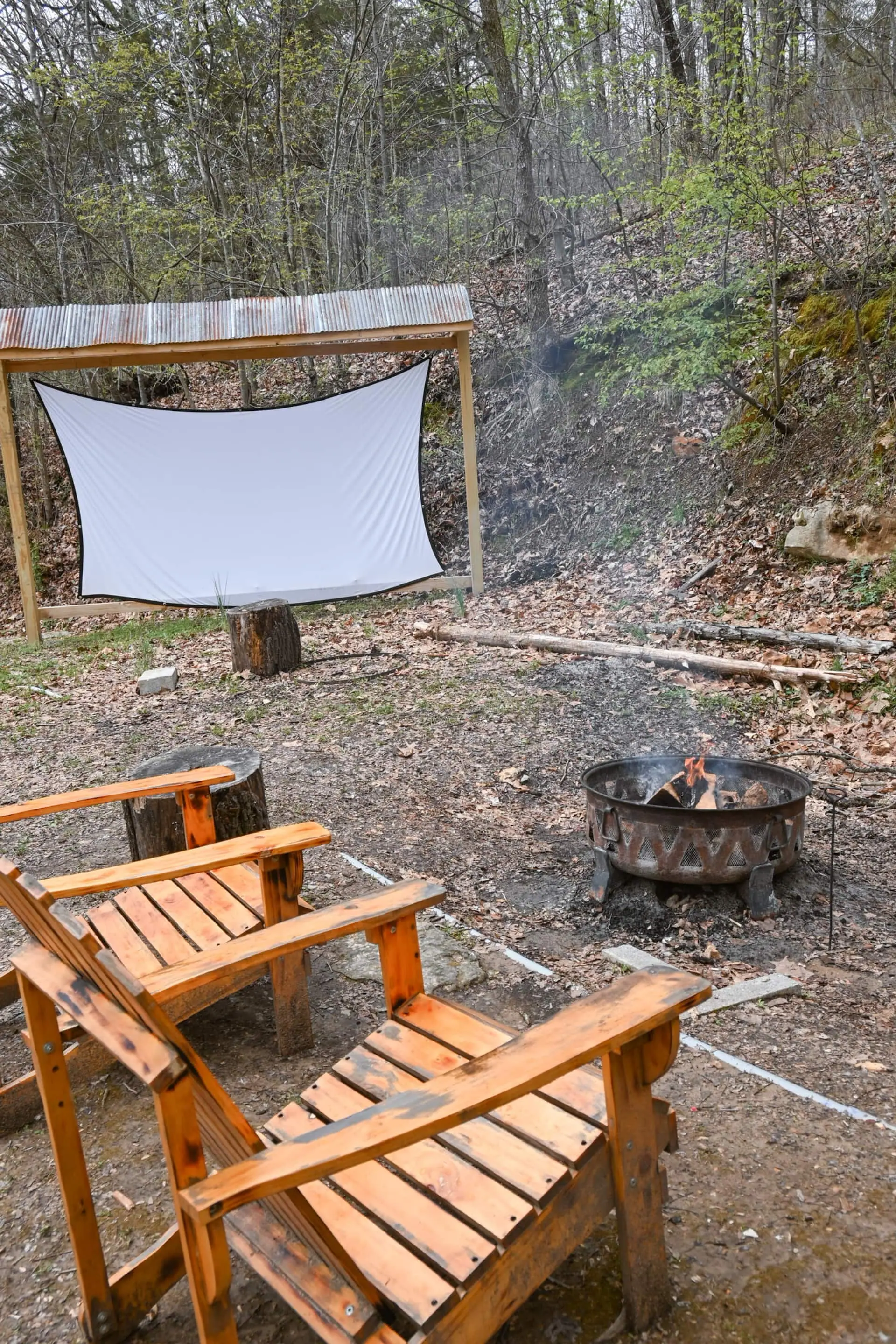 The outdoor movie theatre — a projector screen and fire pit ringed with wooden Adirondack chairs