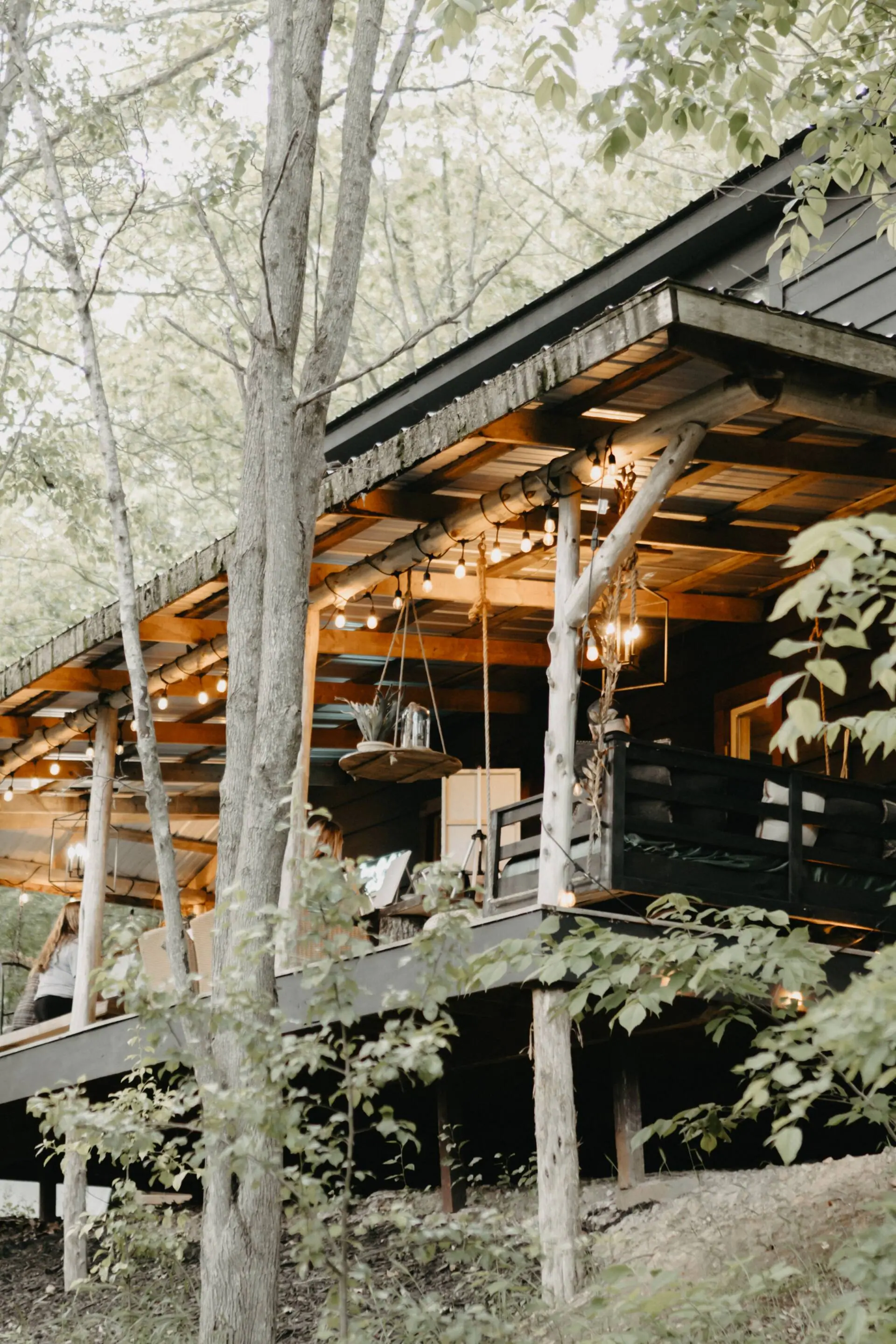 The cabin at dusk with string lights glowing through the trees