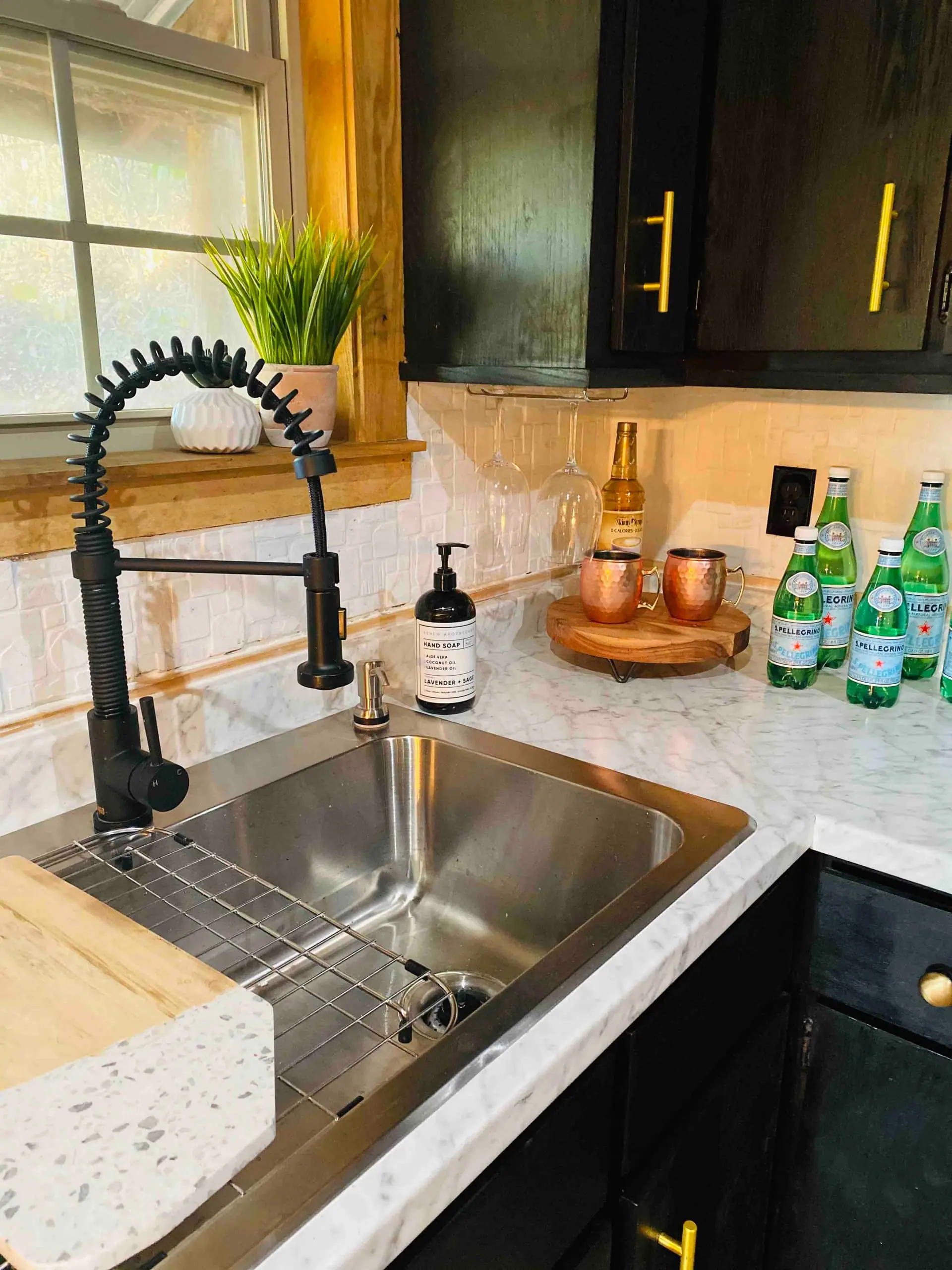 The kitchen sink with stone counters, a matte-black faucet, copper mugs and a chilled bottle of champagne
