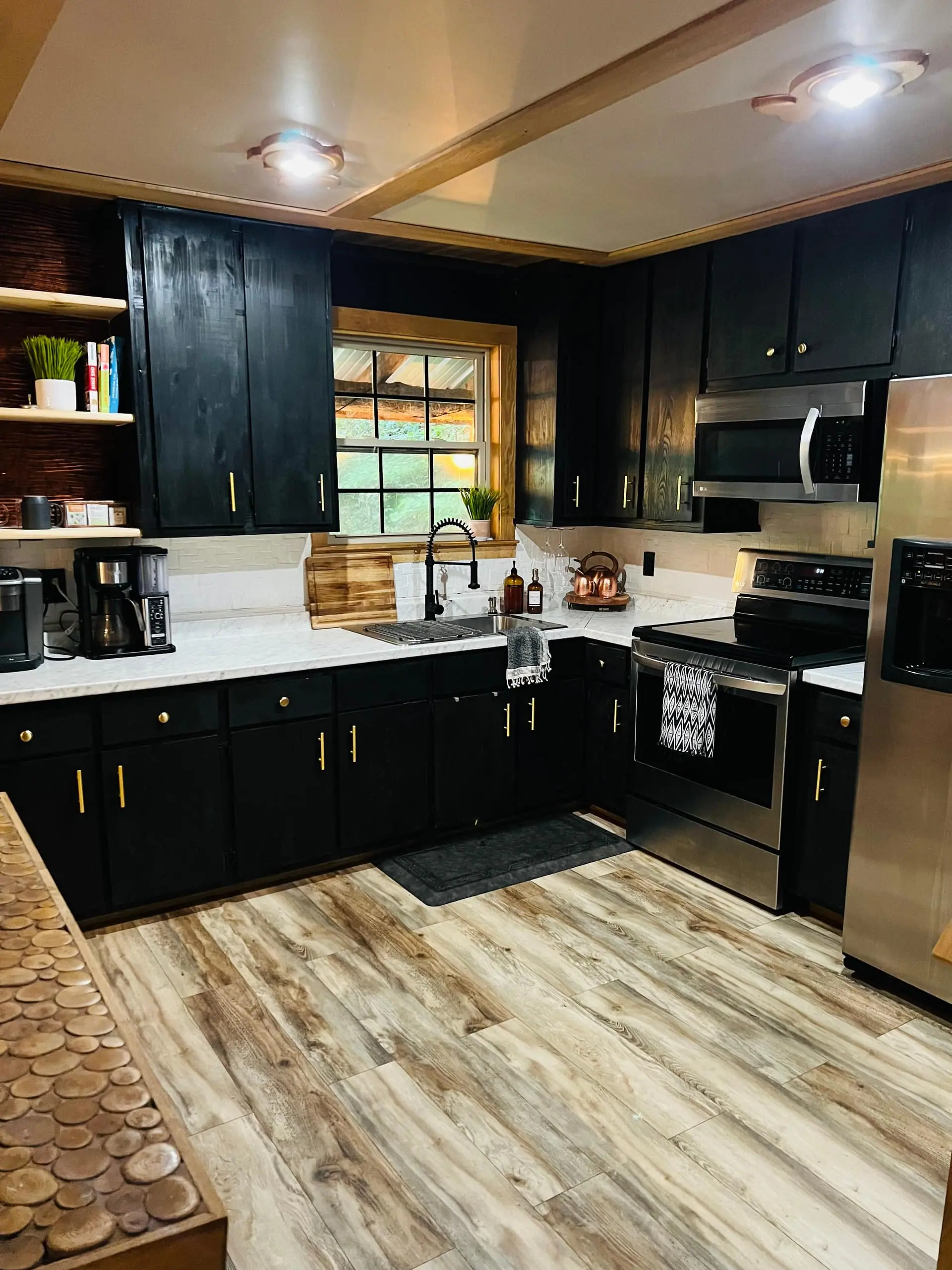 The full kitchen with black cabinets, a stainless range and wide-plank flooring