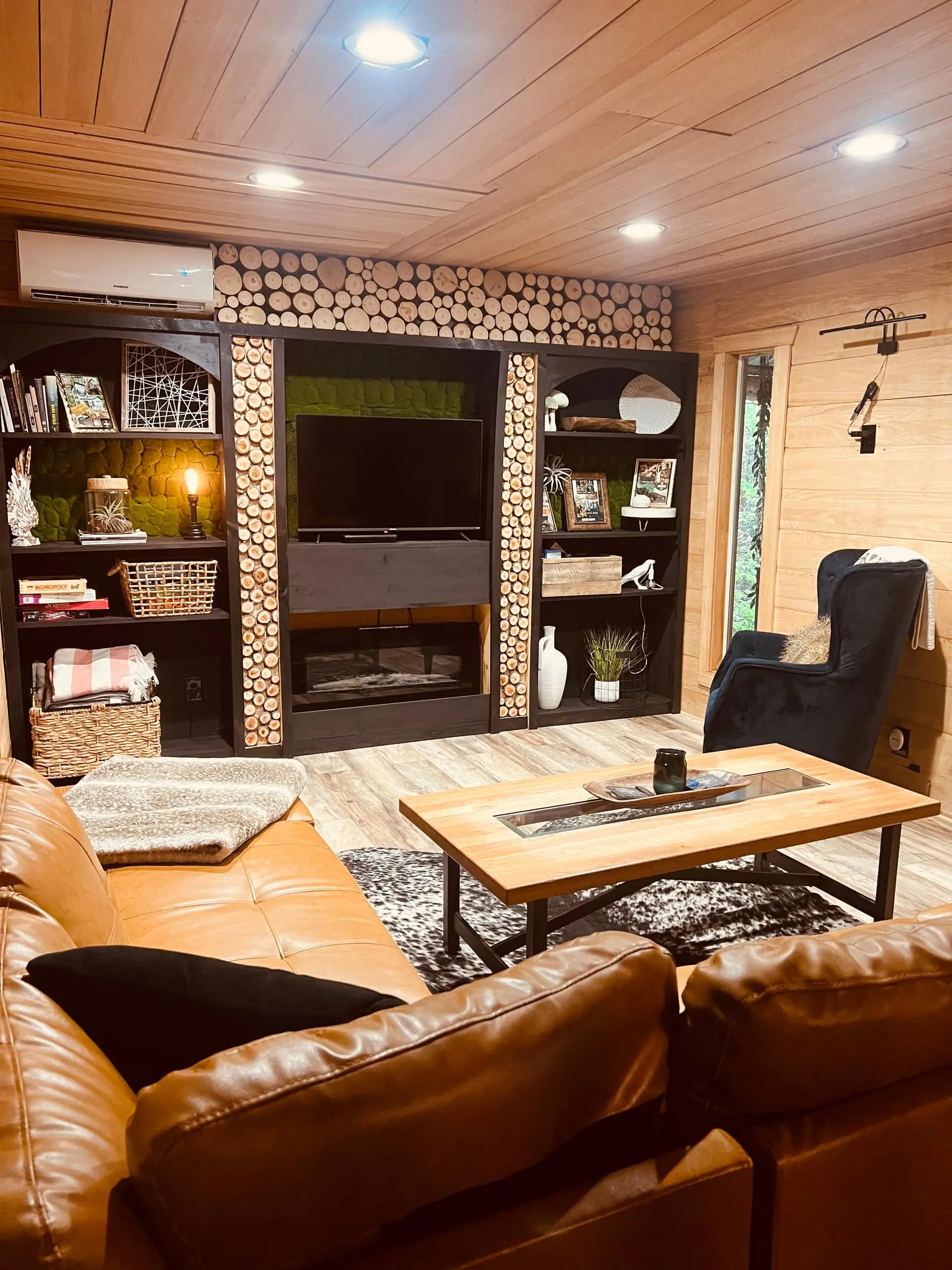 The living room with a leather lounge chair, wood-clad walls, built-in shelving and a TV