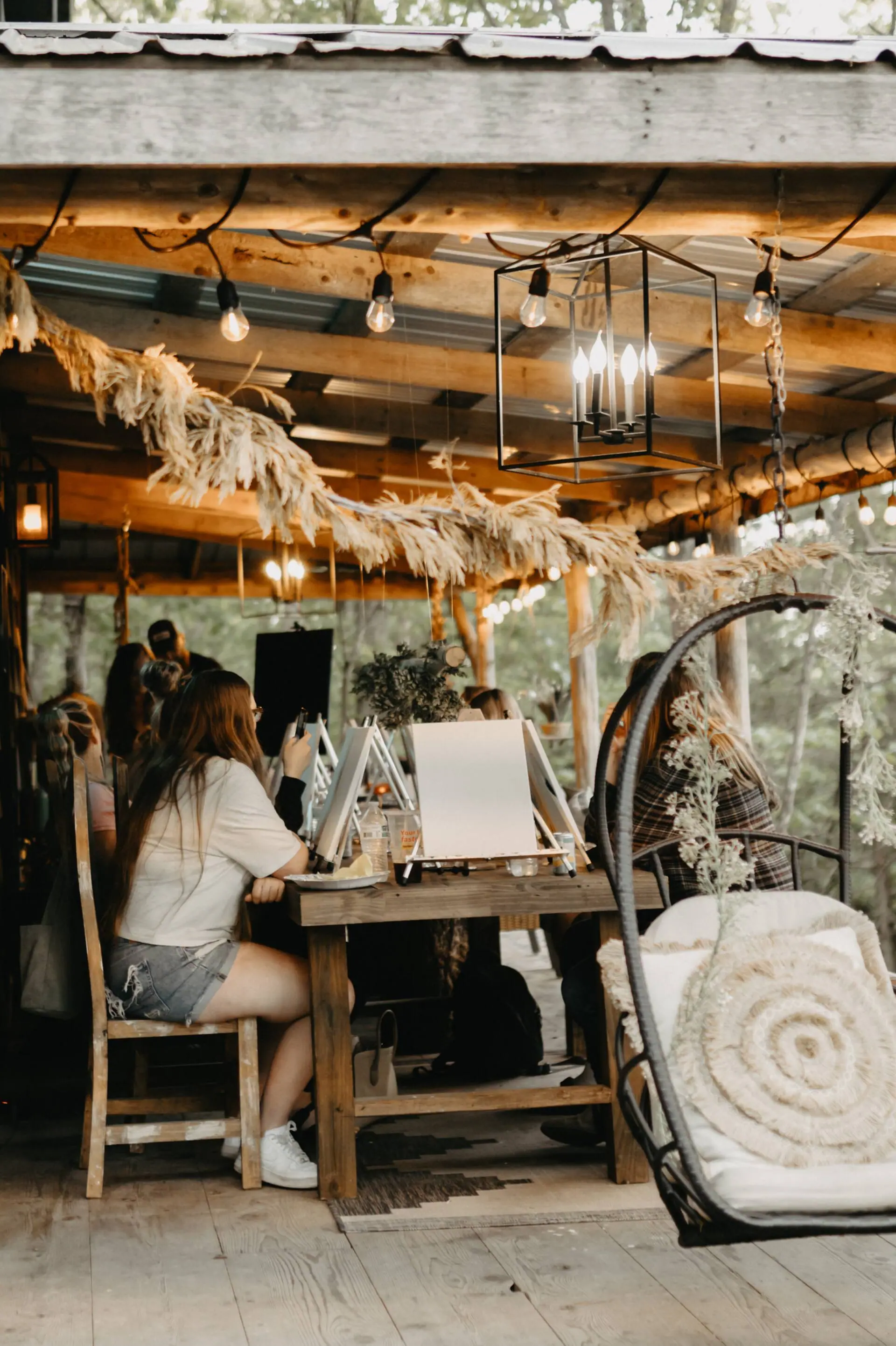 A guest painting at an easel on the cabin porch during a workshop