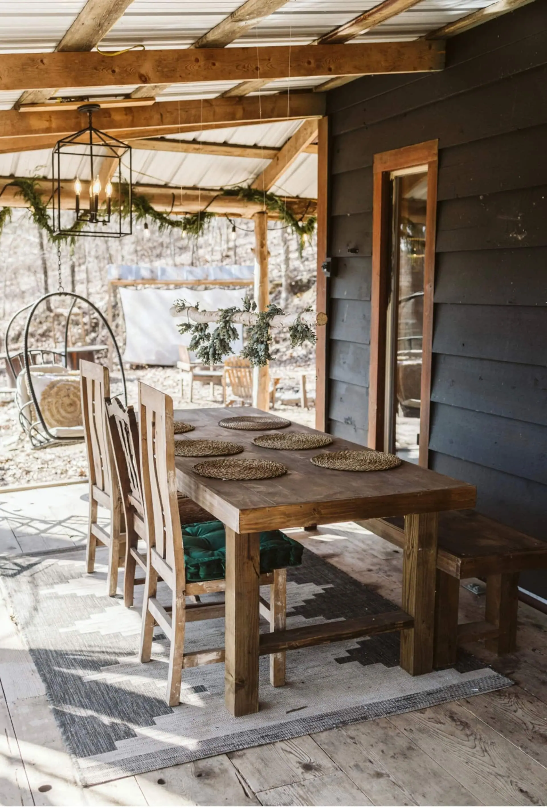The outdoor dining table set with wood-slice placemats, greenery and string lights